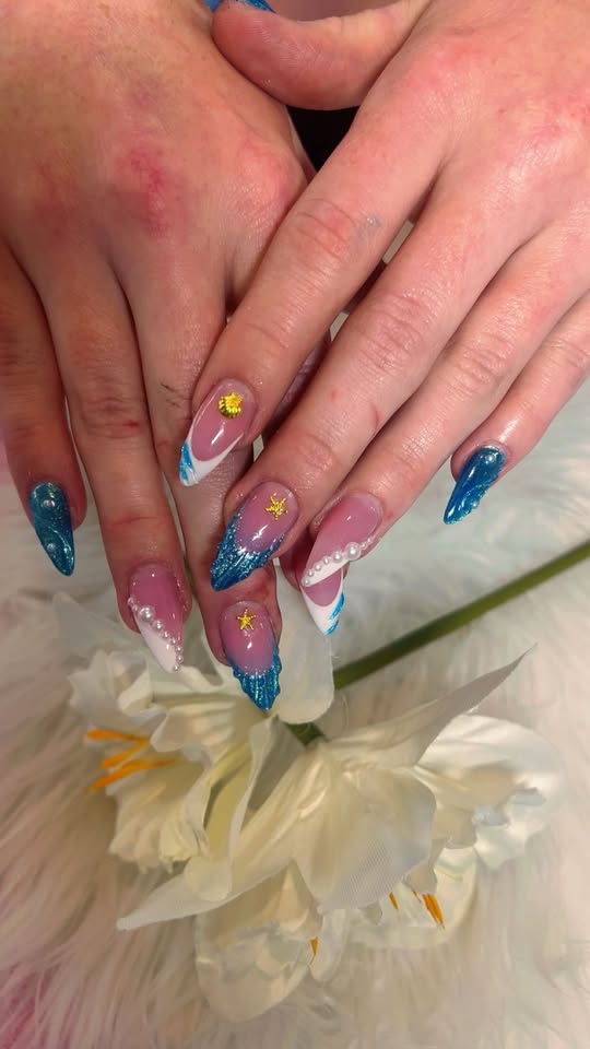 Blue glitter stiletto nails with pearls and gold star charms